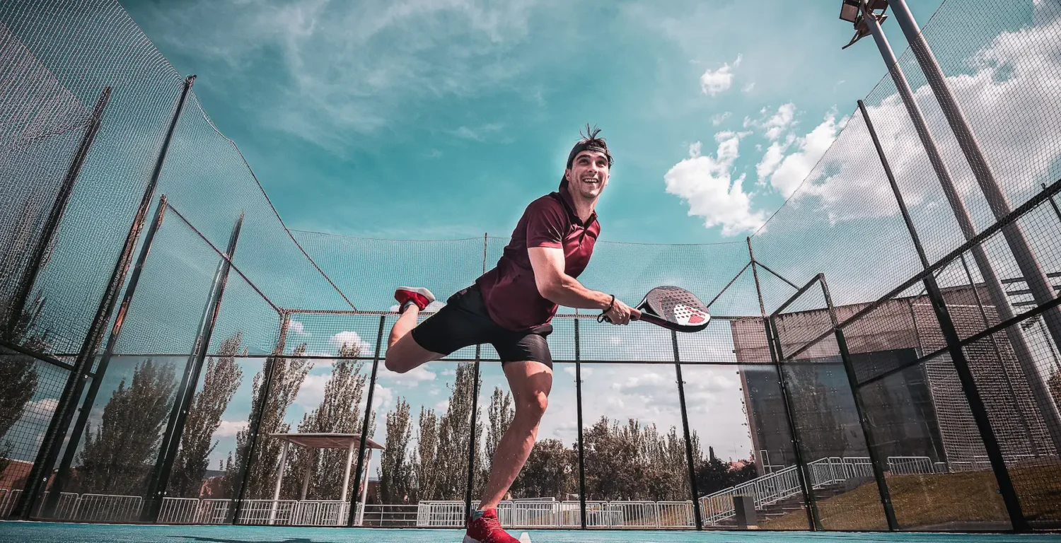 Joueur de padel frappant la balle sur un court extérieur