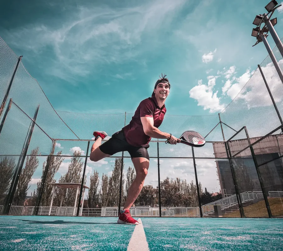 Joueur de padel frappant la balle sur un court extérieur